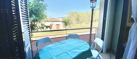 Un balcón con una mesa y sillas, vistas al exterior y un farol.
