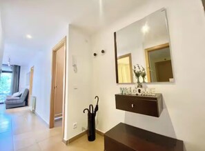 A modern interior with a dark wooden console, a large mirror, and a 'WELCOME' sign above it. - Apartment with a pool near the beach (Sant Feliu de Guíxols)