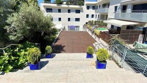 A multi-story residential building with a central courtyard, balconies, and potted plants. - Apartment with a pool near the beach (Sant Feliu de Guíxols)