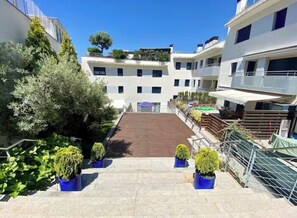 A multi-story residential building with a central courtyard, balconies, and potted plants. - Apartment with a pool near the beach (Sant Feliu de Guíxols)