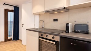 A modern kitchen with a built-in oven, a stove, and a coffee maker. - Studio Tepes - Natassa Samos Seaview Balcony Suite (Samos)