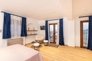 Ein modernes Schlafzimmer mit einem Bett, einem Sessel, einem kleinen Tisch und einem Fernseher.
