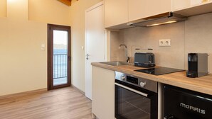 A modern kitchen with wooden flooring, a built-in oven, a toaster, and a coffee maker. - Studio Tepes - Velis Samos Sea View Balcony Suite (Samos)