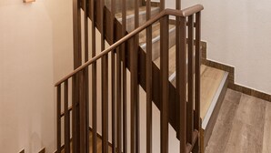 A wooden staircase with a handrail and a light fixture on the wall. - Studio Tepes - Velis Samos Sea View Balcony Suite (Samos)