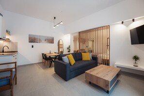 Ein modernes Wohnzimmer mit einem dunklen Sofa, einem Holztisch und einem Essbereich mit einem Holztisch und Stühlen.