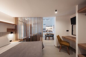 A modern bedroom with a bed, a desk, and a chair. There is a kitchen in the background. - Chalkidiki Serene Retreat With Private Parking (Sithonia)