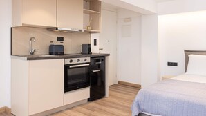 A compact kitchenette with a stove, oven, and a small refrigerator. - Studio Tepes - Niki Samos Sea View Balcony Suite (Samos)