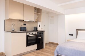 Eine kompakte Küchenzeile mit Herd, Backofen und kleinem Kühlschrank.