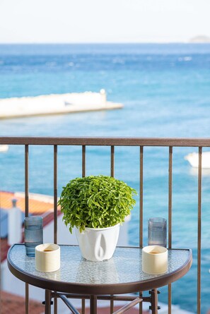 A balcony with a potted plant, two glasses, and a view of the ocean. - Studio Tepes - Samos Sea View Balcony Suites (Samos)