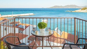 A balcony with a view of the sea, a table with a potted plant, and two chairs. - Studio Tepes - Samos Sea View Balcony Suites (Samos)