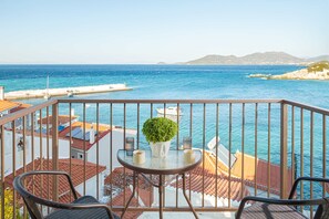 A balcony with a view of the sea, a table with a potted plant, and two chairs. - Studio Tepes - Samos Sea View Balcony Suites (Samos)