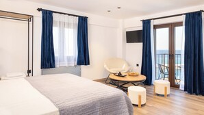 A hotel room with a bed, a chair, a table with a tray, and a balcony with a view. - Studio Tepes - Samos Sea View Balcony Suites (Samos)