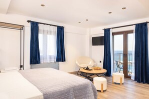 A hotel room with a bed, a chair, a table with a tray, and a balcony with a view. - Studio Tepes - Samos Sea View Balcony Suites (Samos)