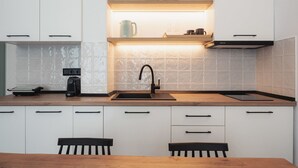 A modern kitchen with white cabinets, a wooden countertop, a built-in sink, and a coffee machine. - Chalkidiki Peaceful Retreat With Private Parking (Sithonia)