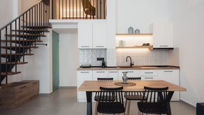 A modern kitchen with white cabinetry, a wooden dining table, and black chairs. - Chalkidiki Peaceful Retreat With Private Parking (Sithonia)