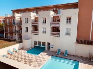 A multi-story residential building with balconies, a swimming pool, and outdoor seating. - Appartement 3 étoiles - Piscine  - ccbgfca (Gréoux-les-Bains)