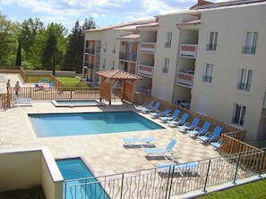 A hotel with a swimming pool, sun loungers, and a small wooden structure. - Appartement 3 étoiles - Piscine  - ccbgfcb (Gréoux-les-Bains)