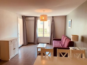 Ett rum med en soffa, ett bord, en lampa och ett fönster med gardiner.