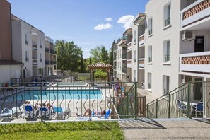 Ein Wohngebäude mit Schwimmbad, Außenbereich mit Sitzgelegenheiten und überdachtem Bereich.