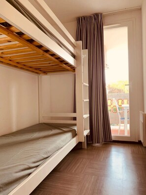 Quarto com beliche, porta de correr e vista para o exterior.