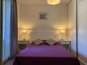 Ein Hotelzimmer mit einem Bett, zwei Nachttischen und einem Fenster mit Vorhängen.