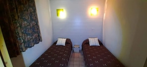 A narrow corridor with two beds, each with a pillow and a small bedside table. - Appartement - Piscine  - ccbgfci (Allevard)