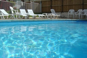 A swimming pool with clear water and white lounge chairs along the edge. - Appartement - Piscine  - ccbgfci (Allevard)