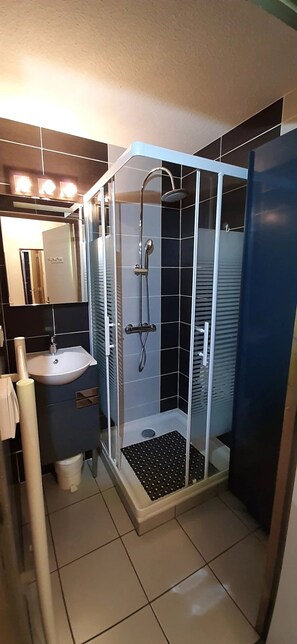 Un baño con ducha de vidrio, lavamanos y espejo.