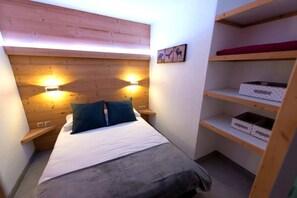 Un dormitorio con una cama, dos mesitas de noche, un estante en la pared y un cuadro colgado.