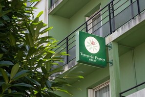 Ein Schild mit der Aufschrift 'Terres de France BREST' an einem Gebäude mit einer grünen Fassade und einem Balkon.