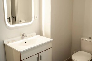 A bathroom with a white sink, mirror, and toilet. - Appartement 2 étoiles - ccbgffb (Brest)