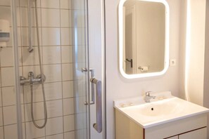 Une salle de bain avec une douche, un lavabo et un miroir.