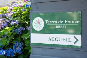 Placa com o texto 'Terres de France BREST' e uma seta apontando para a direita, indicando o caminho para o hotel.