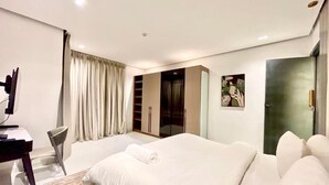 Quarto de hotel moderno com uma cama grande, uma mesa e um guarda-roupa.