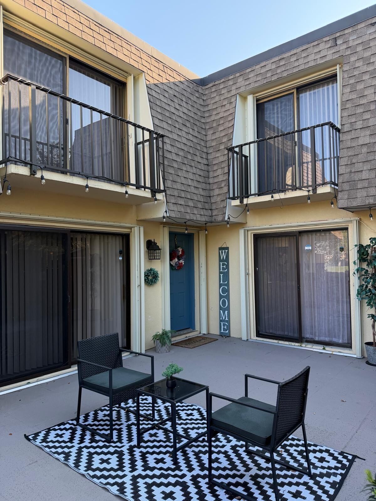 A two-story building with a balcony, a welcome sign, and a patterned rug.