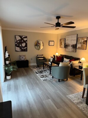 Ein Wohnzimmer mit Deckenventilator, einer Couch, einem Couchtisch und einem Teppich.