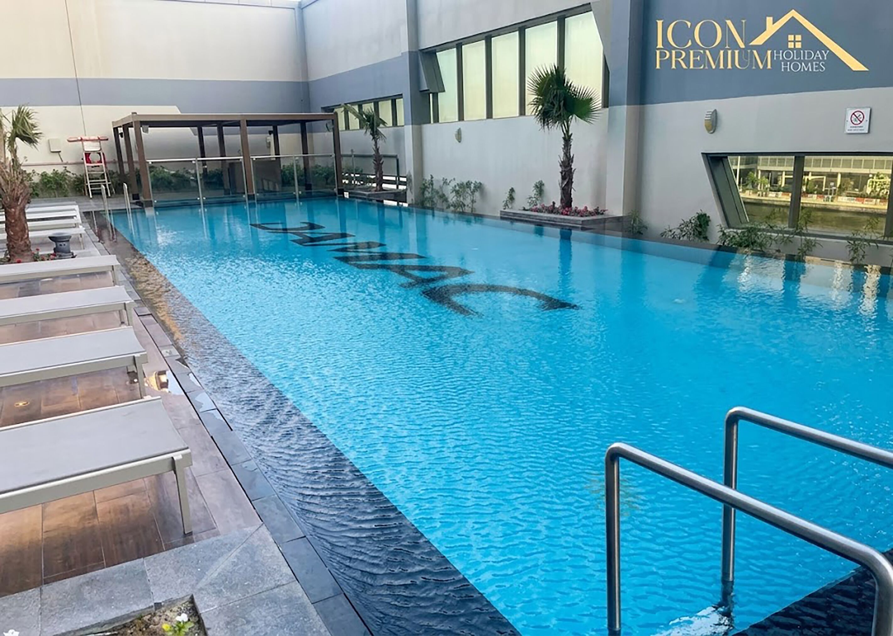 Une piscine offrant une vue dégagée sur l’espace autour de la piscine, y compris les marches et un espace de repos couvert.