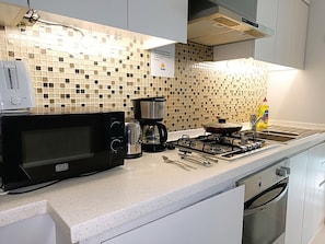 A kitchen with a microwave, coffee maker, gas stove, and a sink. - Iconic Waterside Studio  Near Dubai Mall (Dubai)