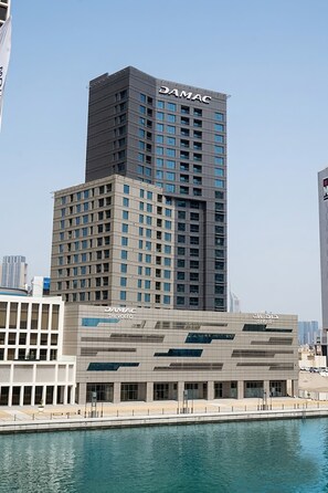 A high-rise building with the name 'DAMAC' on the top. - Iconic Waterside Studio  Near Dubai Mall (Dubai)