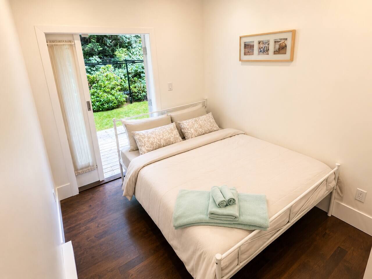 A bedroom with a bed, a door leading to a balcony, and a framed picture on the wall.