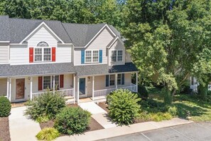 A two-story residential house with a front porch, a garage, and a well-maintained lawn.