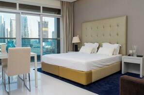 A hotel room with a large bed, a desk, a chair, and a view of the cityscape. - Waterfront Studio Near Dubai Mall Downtown Dubai (Dubai)