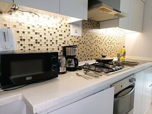 A kitchen with a microwave, coffee maker, gas stove, and a sink. - Waterfront Studio Near Dubai Mall Downtown Dubai (Dubai)