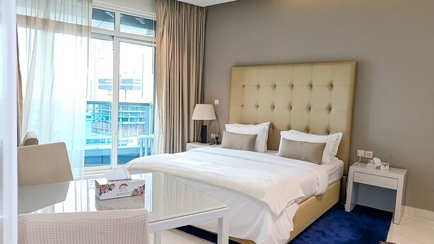 Hotellihuone, jossa on suuri sänky, työpöytä, tuoli, yöpöytä ja näkymä kaupunkiin.