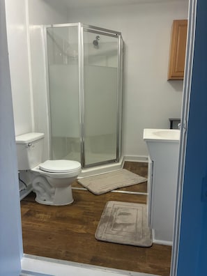 A bathroom with a toilet, a shower enclosure, and a sink.