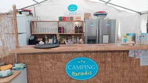 A bar area with a sign reading 'CAMPING Paradise' and a 'Bellerive' sign above it.