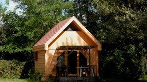 A small wooden cabin with a red roof, a porch with chairs, and a table. - Chalet 3 étoiles - ccbgcca (Montfrin)
