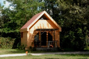 A small wooden cabin with a red roof, a porch with chairs, and a table. - Chalet 3 étoiles - ccbgcca (Montfrin)