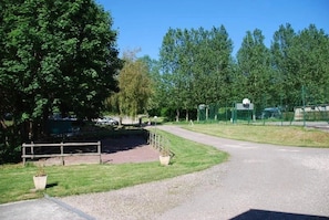 A gravel path leading to a fenced area with a wooden fence and a paved road.