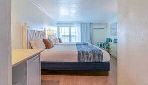 Ein Hotelzimmer mit zwei Betten, einem Schreibtisch, einem Stuhl und einem Fenster mit Vorhängen.